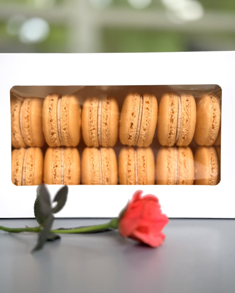 A white window box packed with two rows of orange macarons
