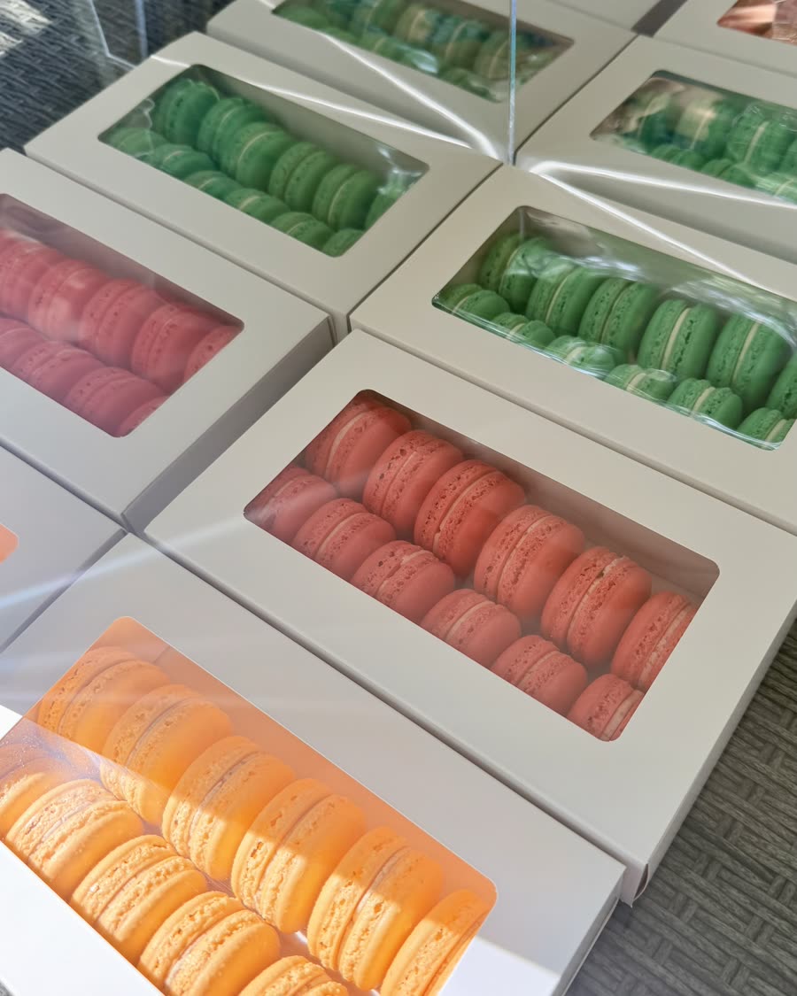 Window boxes of green, red and orange macarons laid out on a table