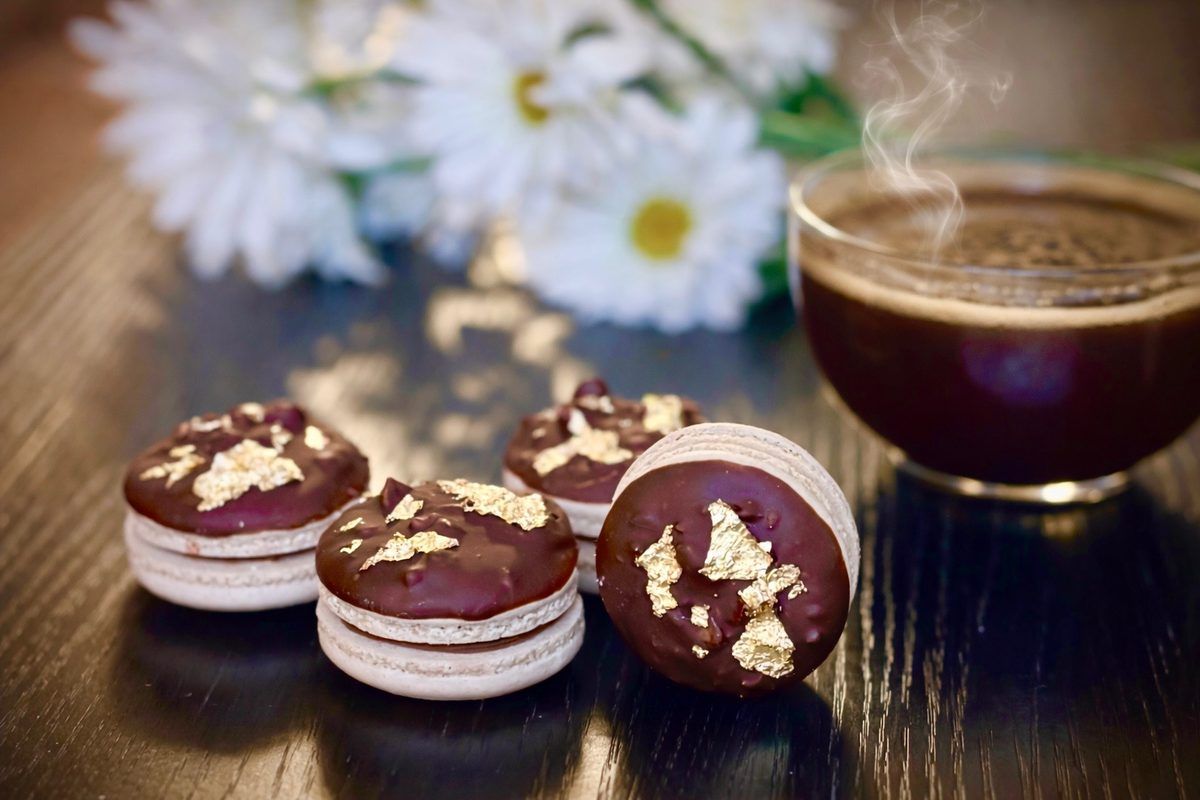 Chocolate hazelnut macarons dipped in chocolate and decorated with gold leaf