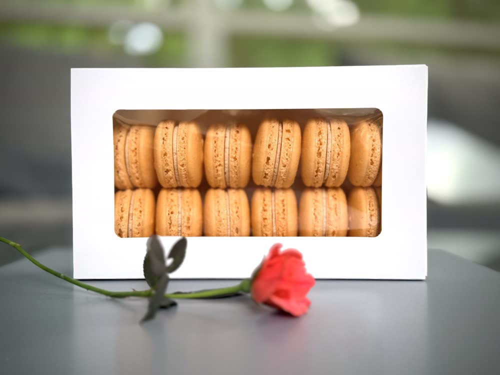 A white window box packed with two rows of orange macarons